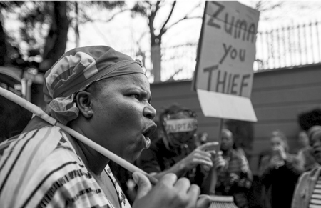 Demonstrators protesting against South African President Jacob Zuma and calling for his resignation hold placards and shout slogans outside the Gupta Family compound in Johannesburg on April 7, 2017.