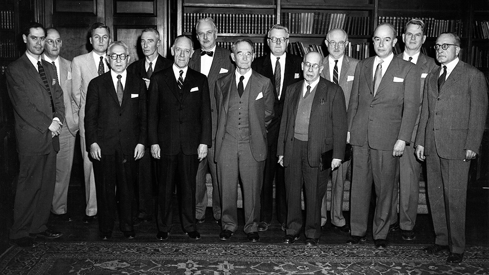 A black and white photo of the presenters from the Conference on Science and the Modern Worldview, held at the Academy in May, 1956. The presenters wear suits and ties and stand in front of bookshelves.