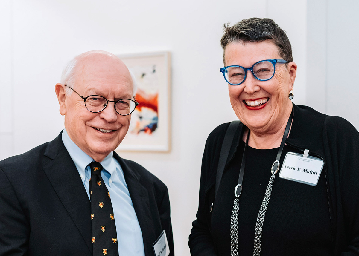 Two individuals standing next to each other, smiling, and looking toward the viewer.