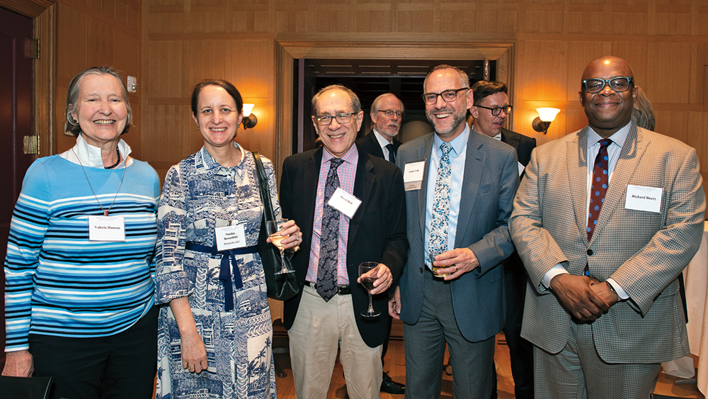 Five people, standing next to each other, are smiling and posing for a picture.