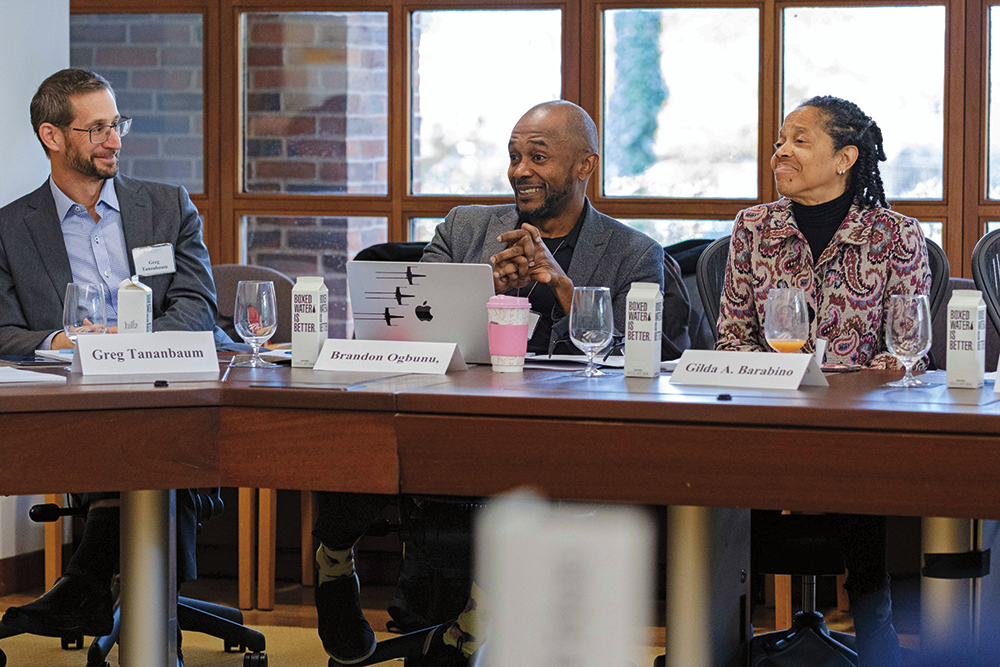 Three people are sitting around a table, engaged in a discussion. &nbsp;