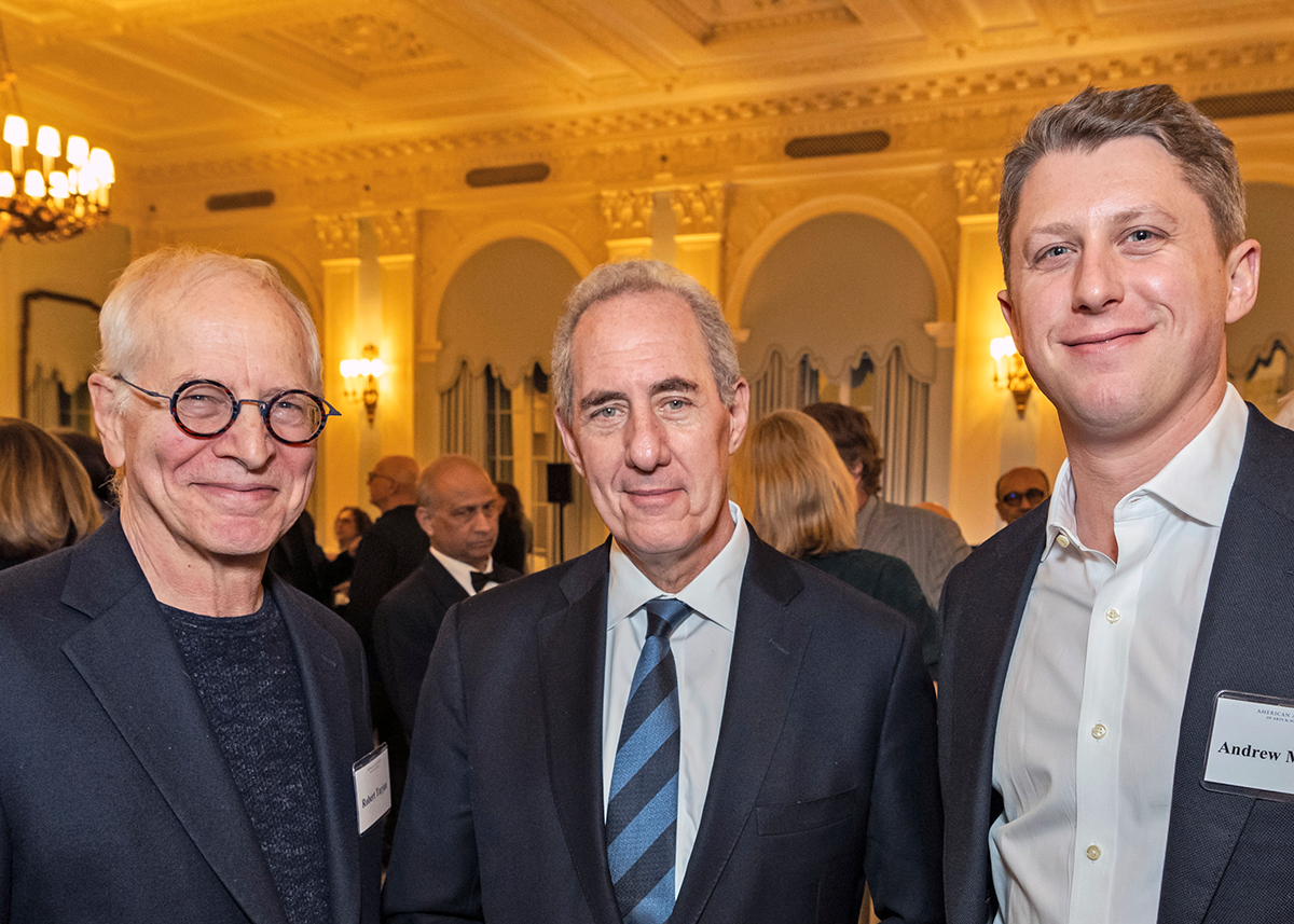 Three formally dressed adults pose at an evening reception.