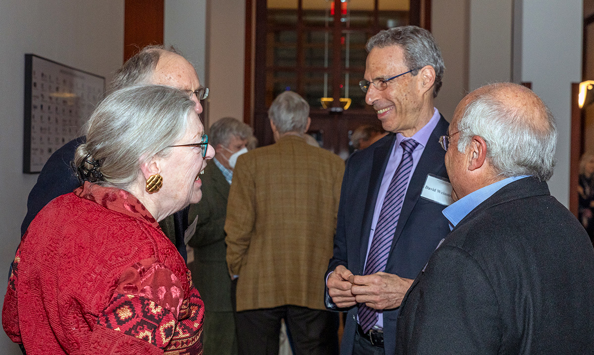 Four individuals in conversation. They are smiling at each other.