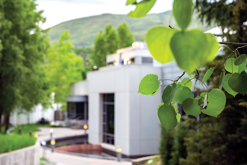 An image of The Walter Isaacson Center at the Aspen Institute surrounded by trees and green leaves.