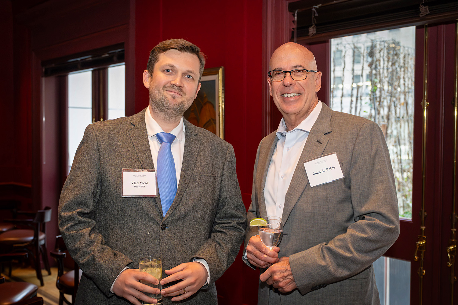 Two formally dressed adults pose and smile in a reception space.