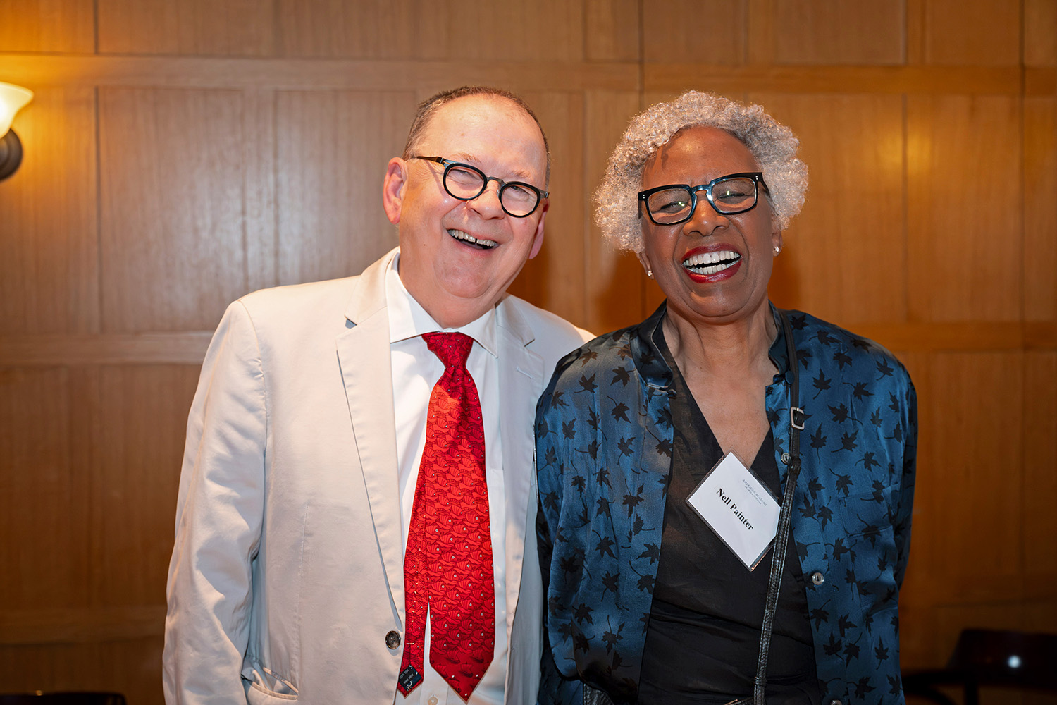 Two formally dressed adults pose and smile at a reception. 