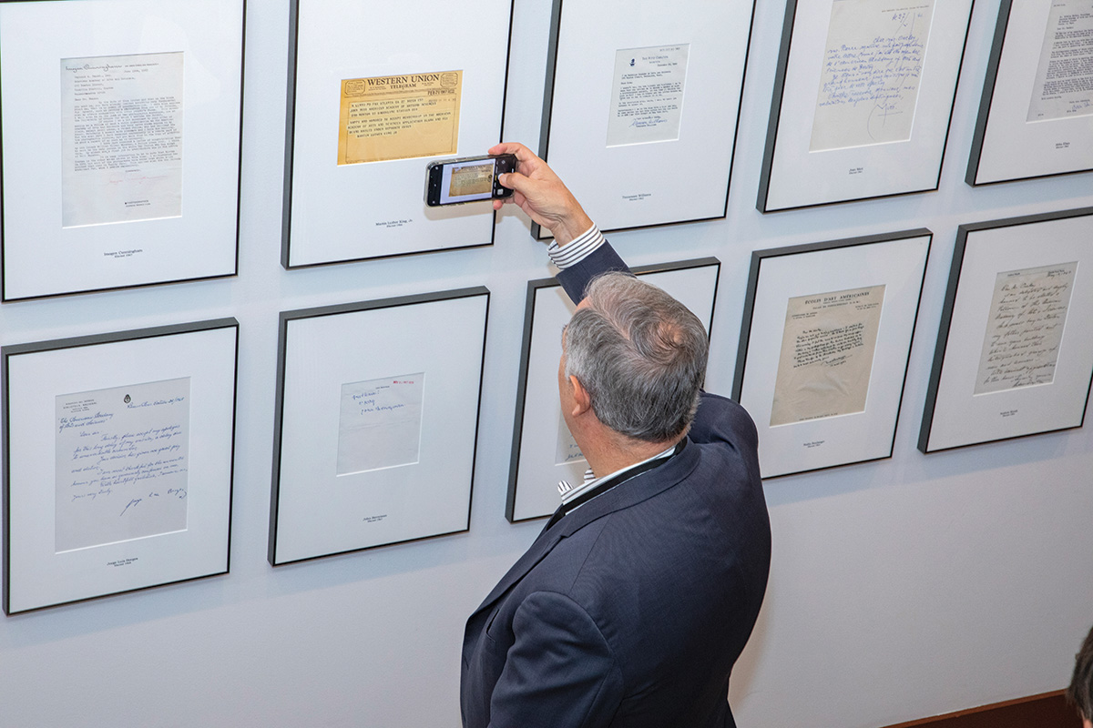 A visitor at the Open House event before the 2023 Induction ceremony takes a photo of acceptance letters among rows of them at the House of the Academy.