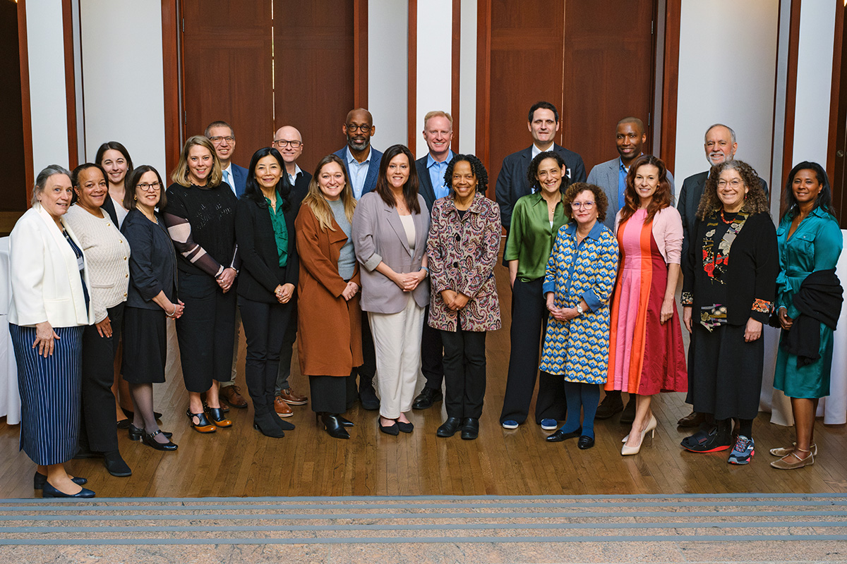21 people are standing together and smiling at the viewer. 