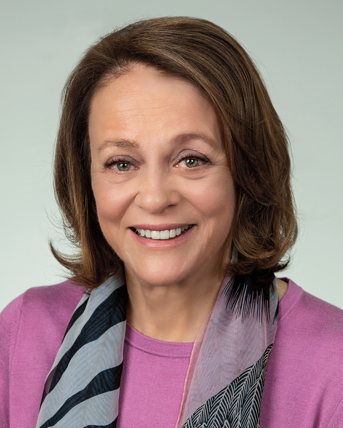 A headshot of Louise Henry Bryson, who has pale skin and shoulder-length brown hair. She faces the viewer and smiles.