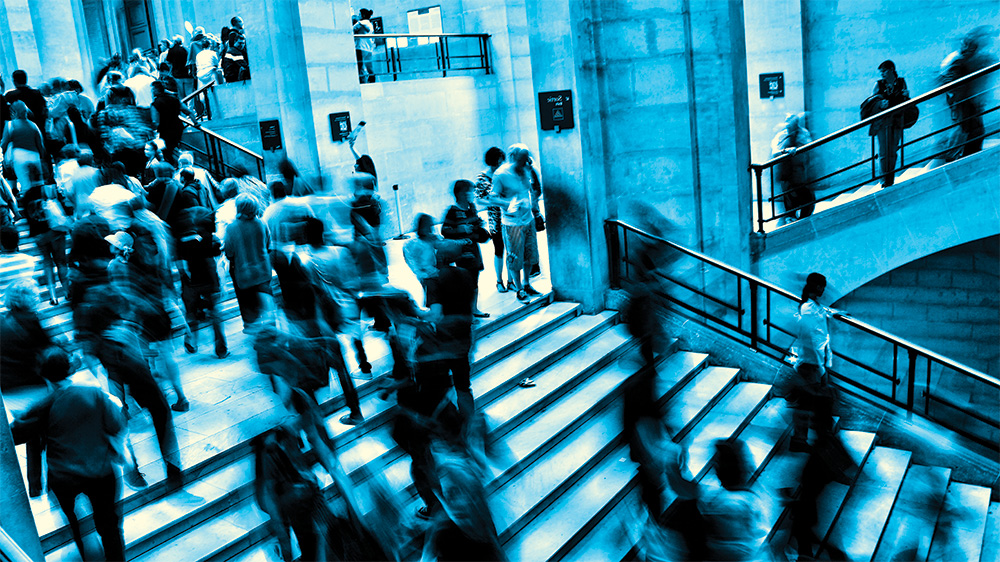 An illustration of a large hall filled with people moving quickly through a stairwell.