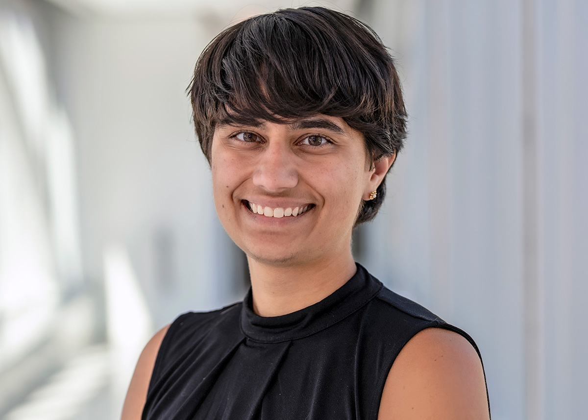 A photograph of an individual with short black hair, facing and smiling at the viewer.
