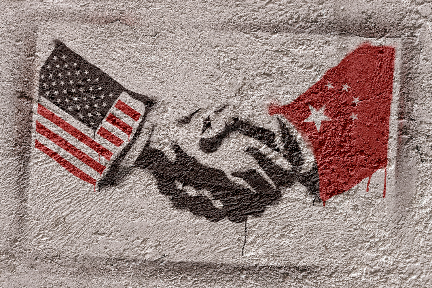 Graffiti painted on a stone wall that shows two hands shaking, with one sleeve featuring the U.S. flag and the other featuring the Chinese flag.