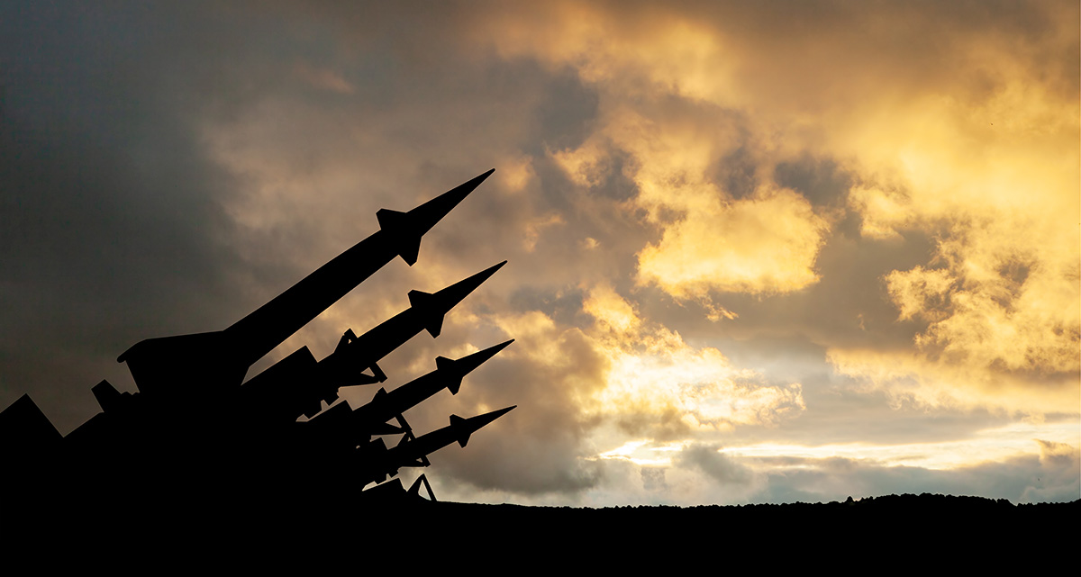 Four missiles are aimed at the sky at sunset.