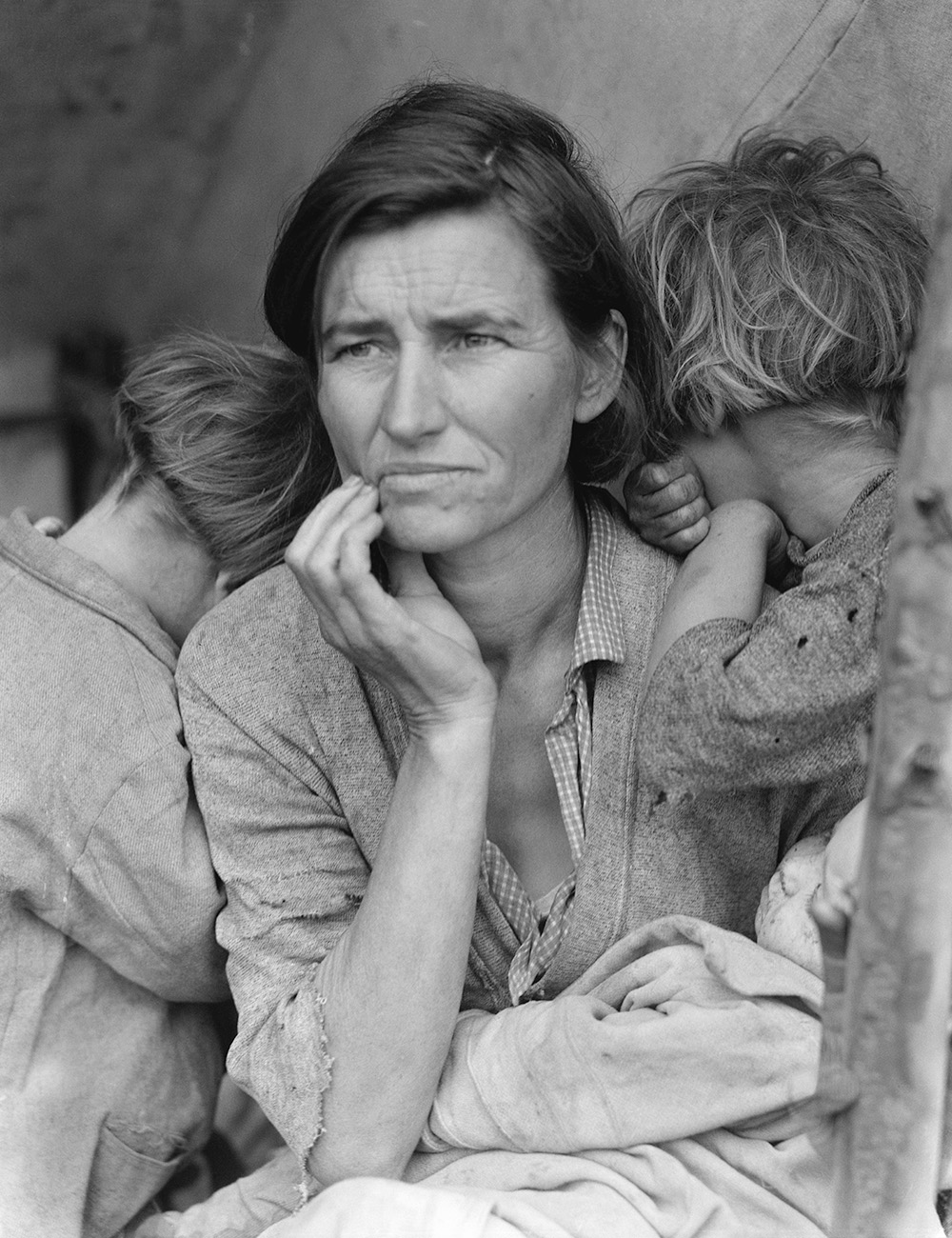 A person holding two children, with an expression of uncertainty and worry. 