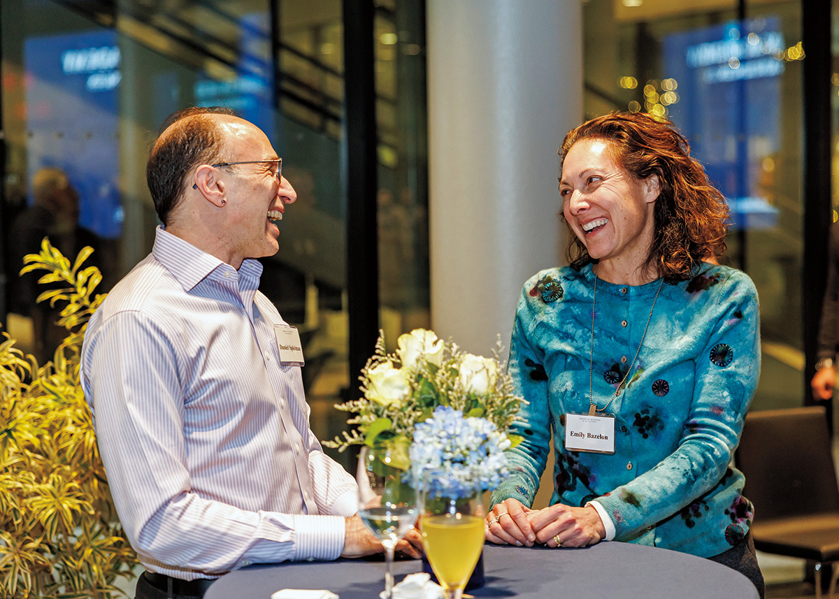 A man and a woman speak at a reception. 