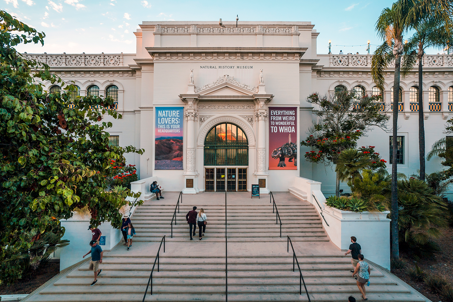 An exterior shot of the front of the San Diego Natural History Museum, a large stone building with a grand staircase and an arched entryway.&nbsp;