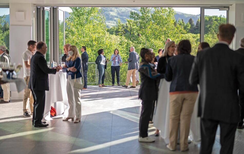 University leaders and attendees engage in deep conversation in a relaxed mountain setting. 