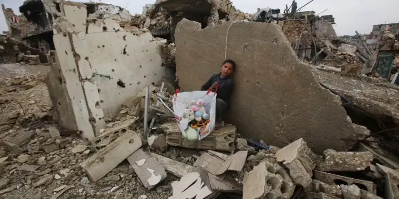 A Syrian boy sits with belongings he collected from the rubble of his house in Aleppo's Al-Arkoub neighbourhood on Dec. 17, 2016, after pro-government forces retook the area from Syrian rebel fighters.