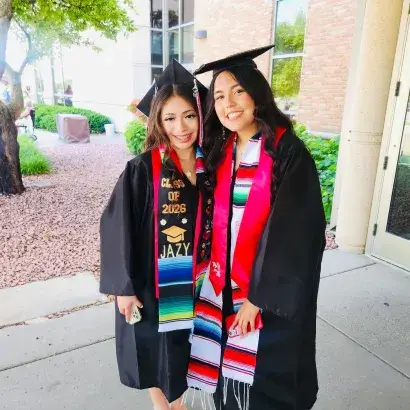 Two young women stand together in cap and gowns.