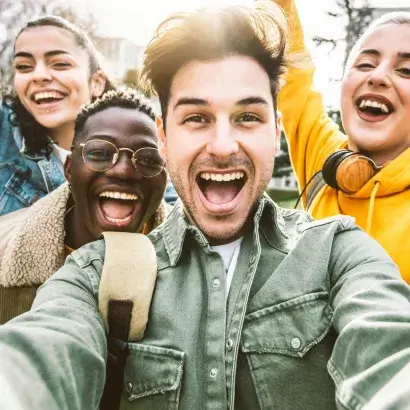 A diverse group of teenagers posing for a selfie with bright, wide smiles