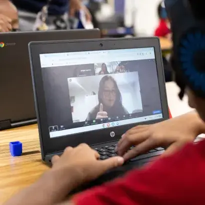 View from behind a grade school student using a computer for virtual tutoring.