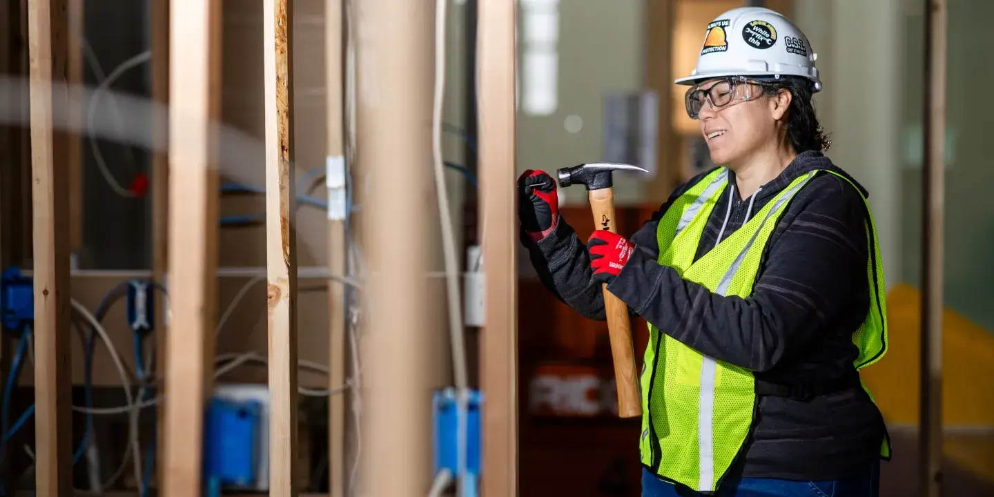 A female construction worker using a tool to build something on a wall