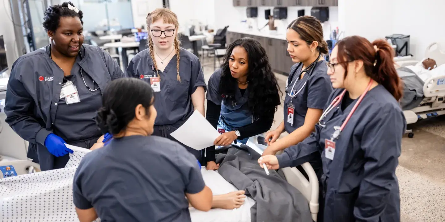 A group of nursing students practice on a dummy with a teaching nurse