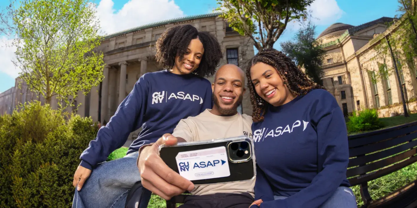 Three students posing for a selfie, the phone that the picture is being taken with has a transit card in the back of the phone. 