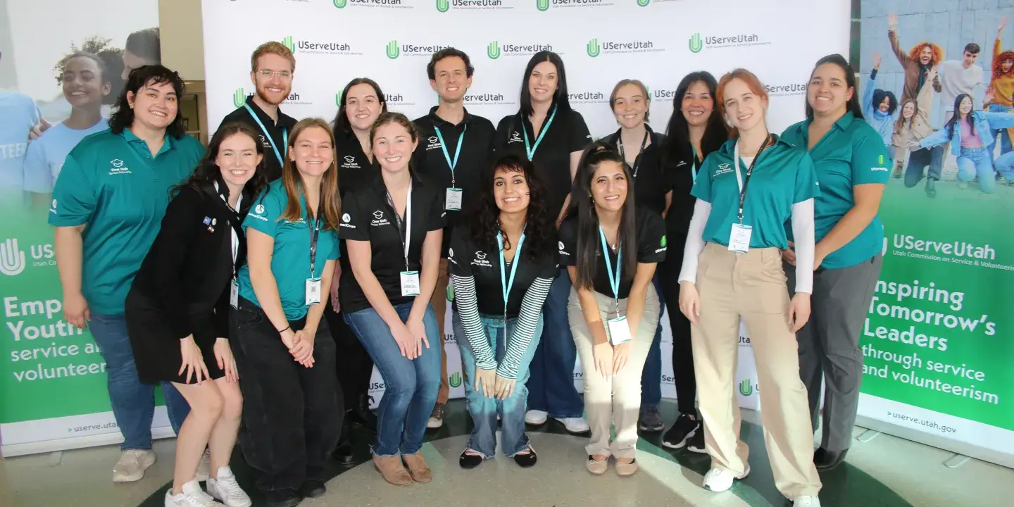A group of people posing in front of a background with the logo "UServeUtah" across the back