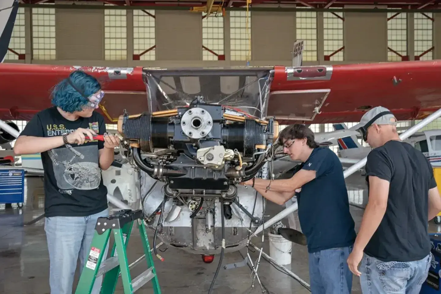 A group of students working on an airplane motor