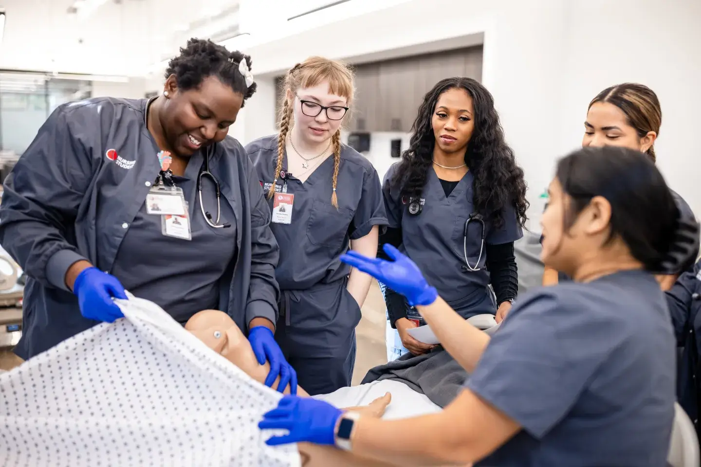 A group of nursing students practice on a dummy with a teaching nurse