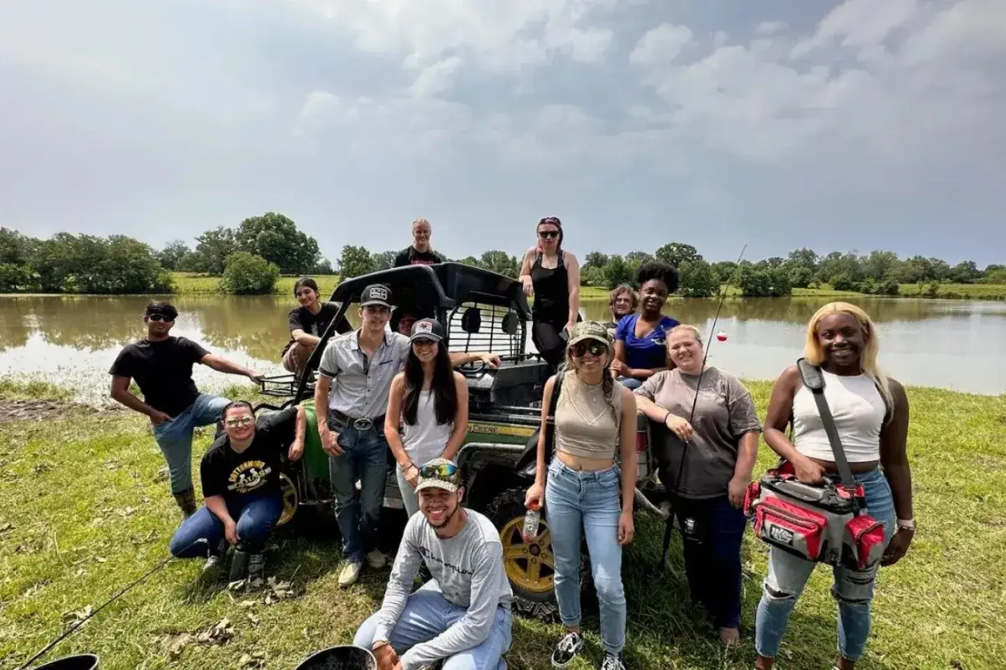 A group of young people posing for a photo around a small vehicle near a body of water