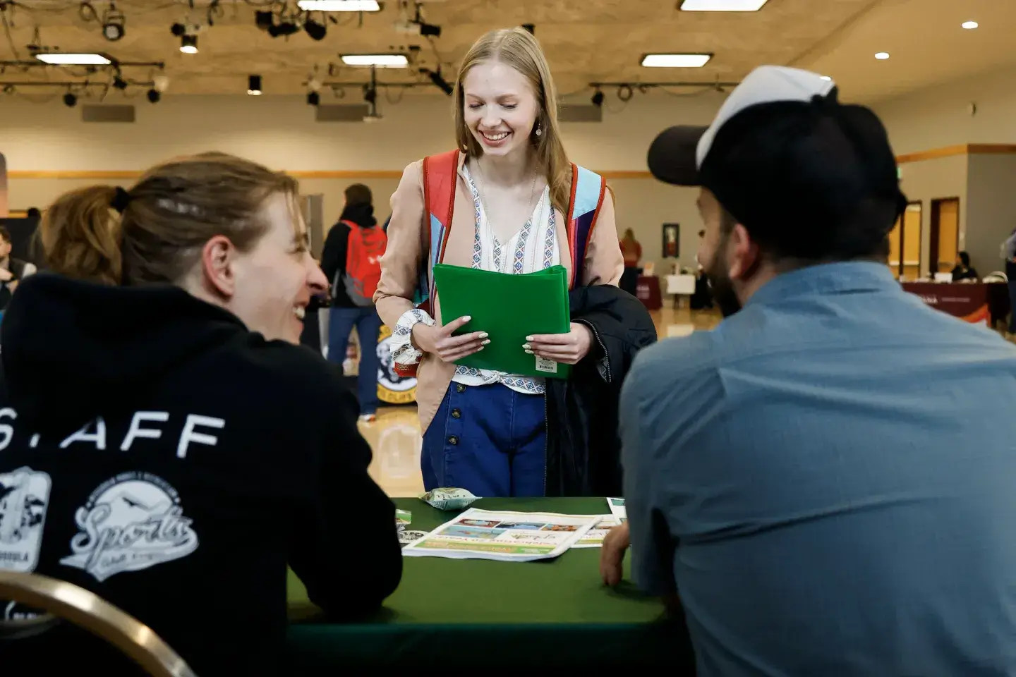 A young student talking to two older students at a college fair 