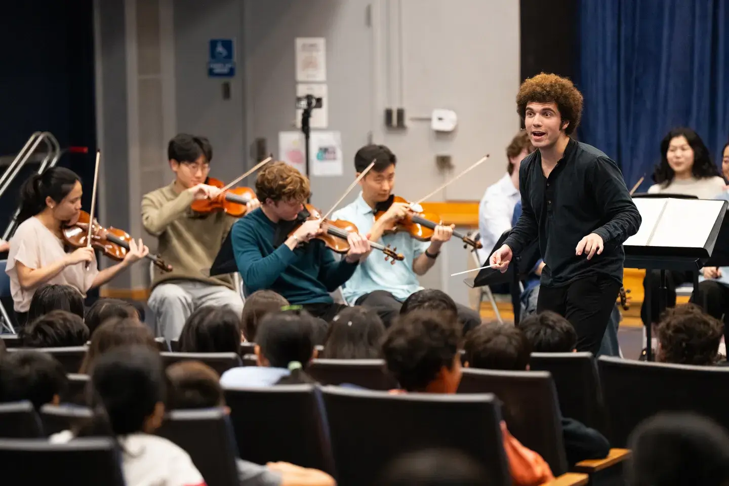A group of musicians practicing in an auditorium