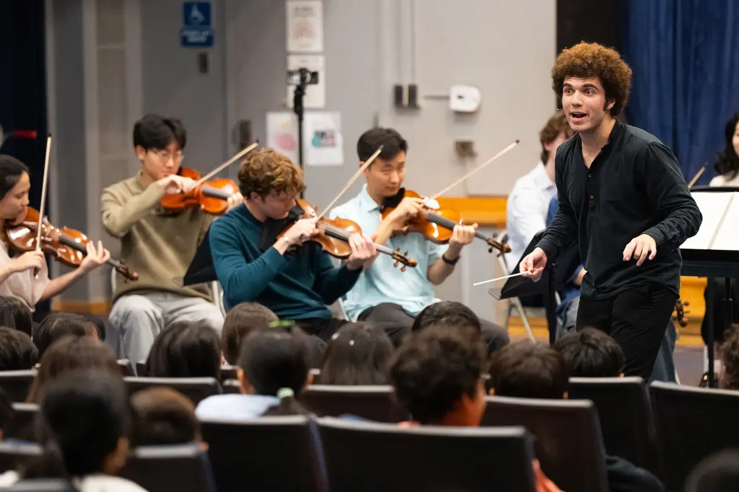 A group of student musicians practicing in an auditorium