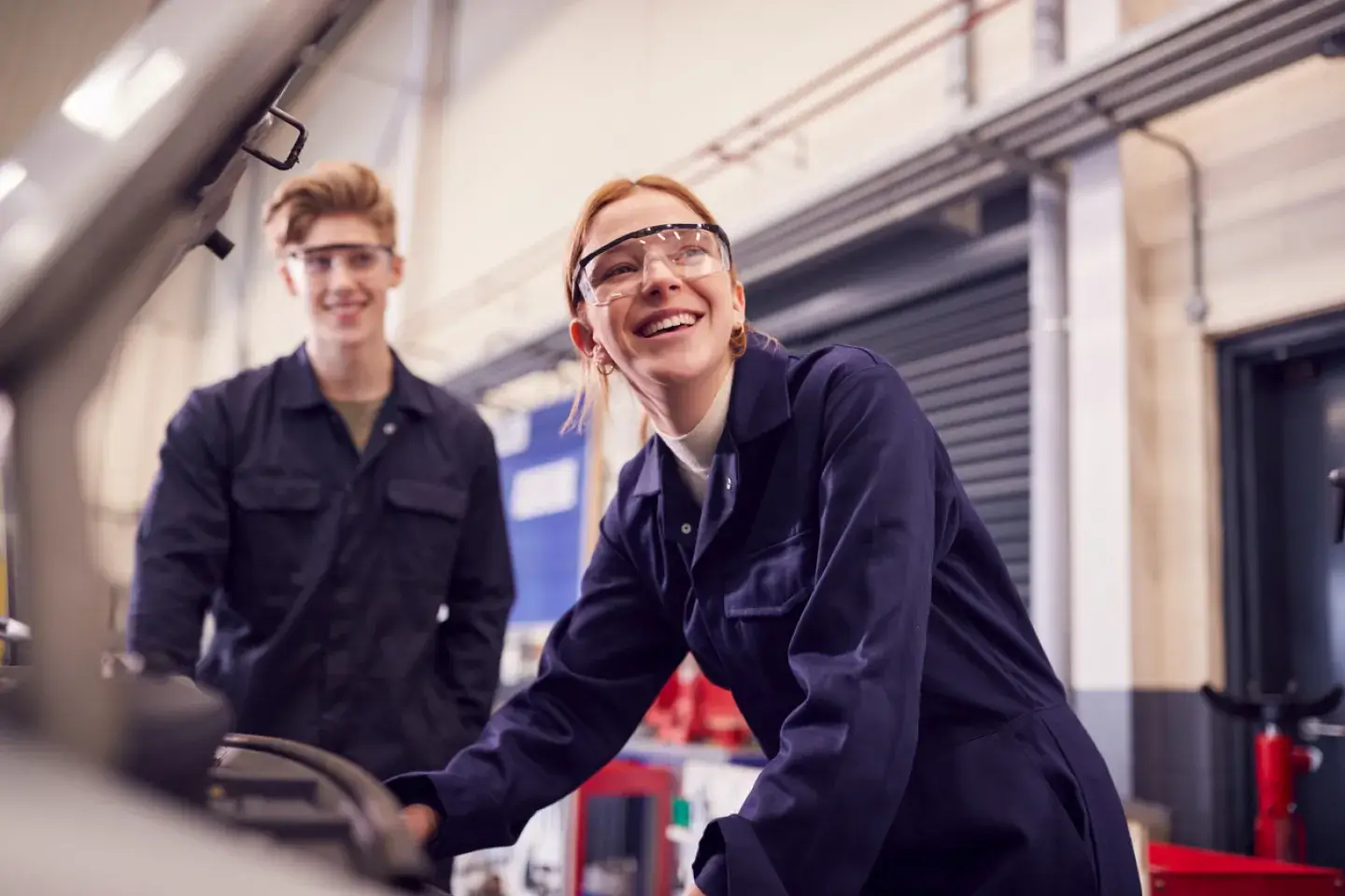 Male And Female Students Looking At Car Engine during Mechanic Apprenticeship Course At College 