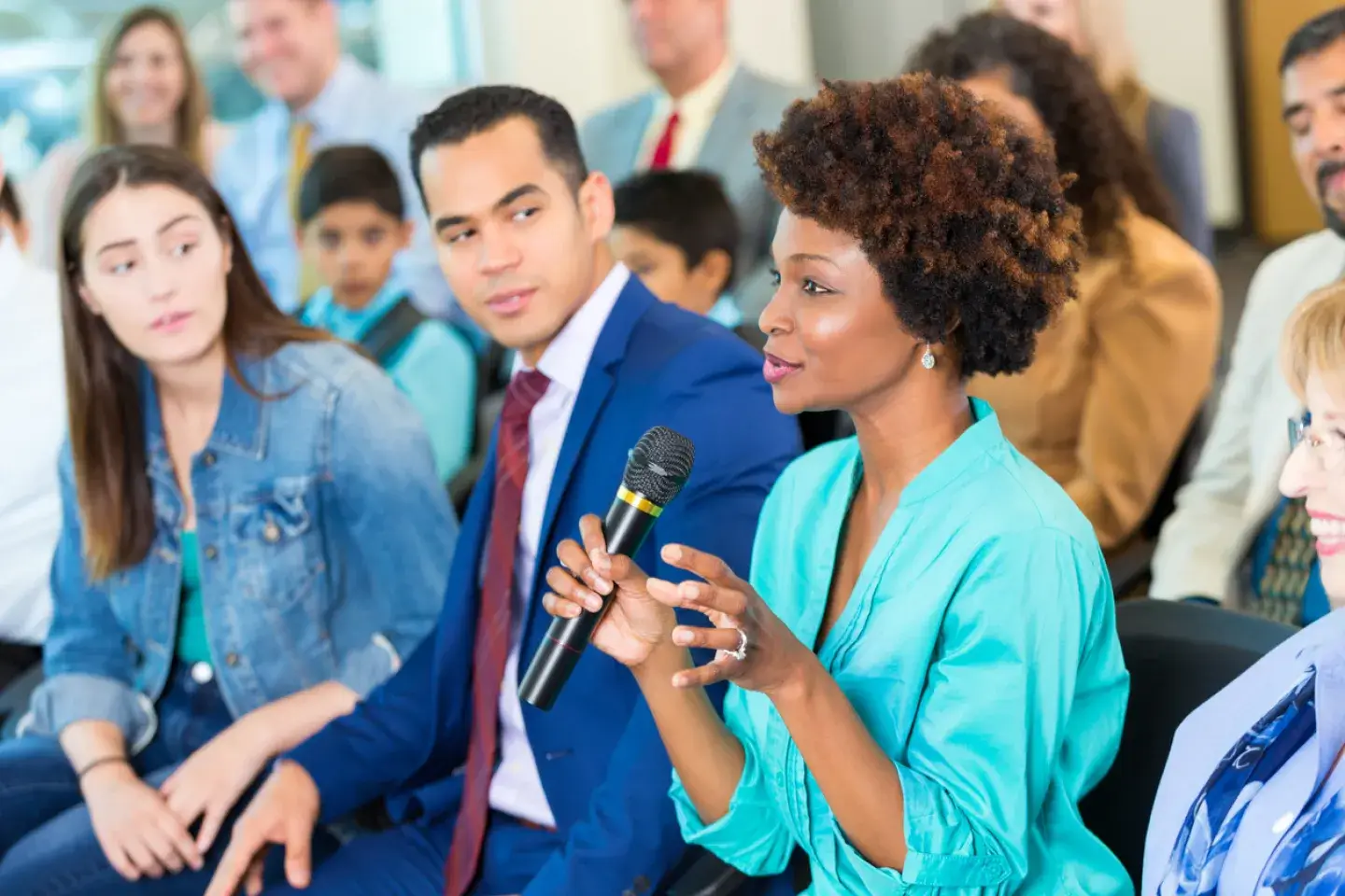 African American woman asks question during a town hall or seminar style meeting