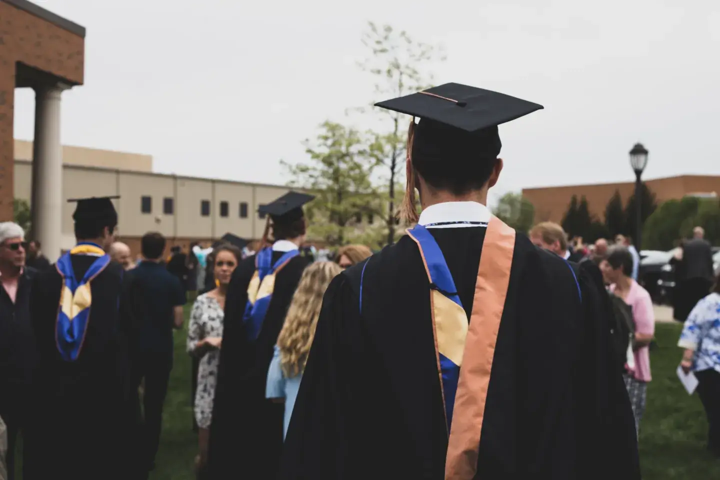 A man in a graduation cap and gown walks away from the camera