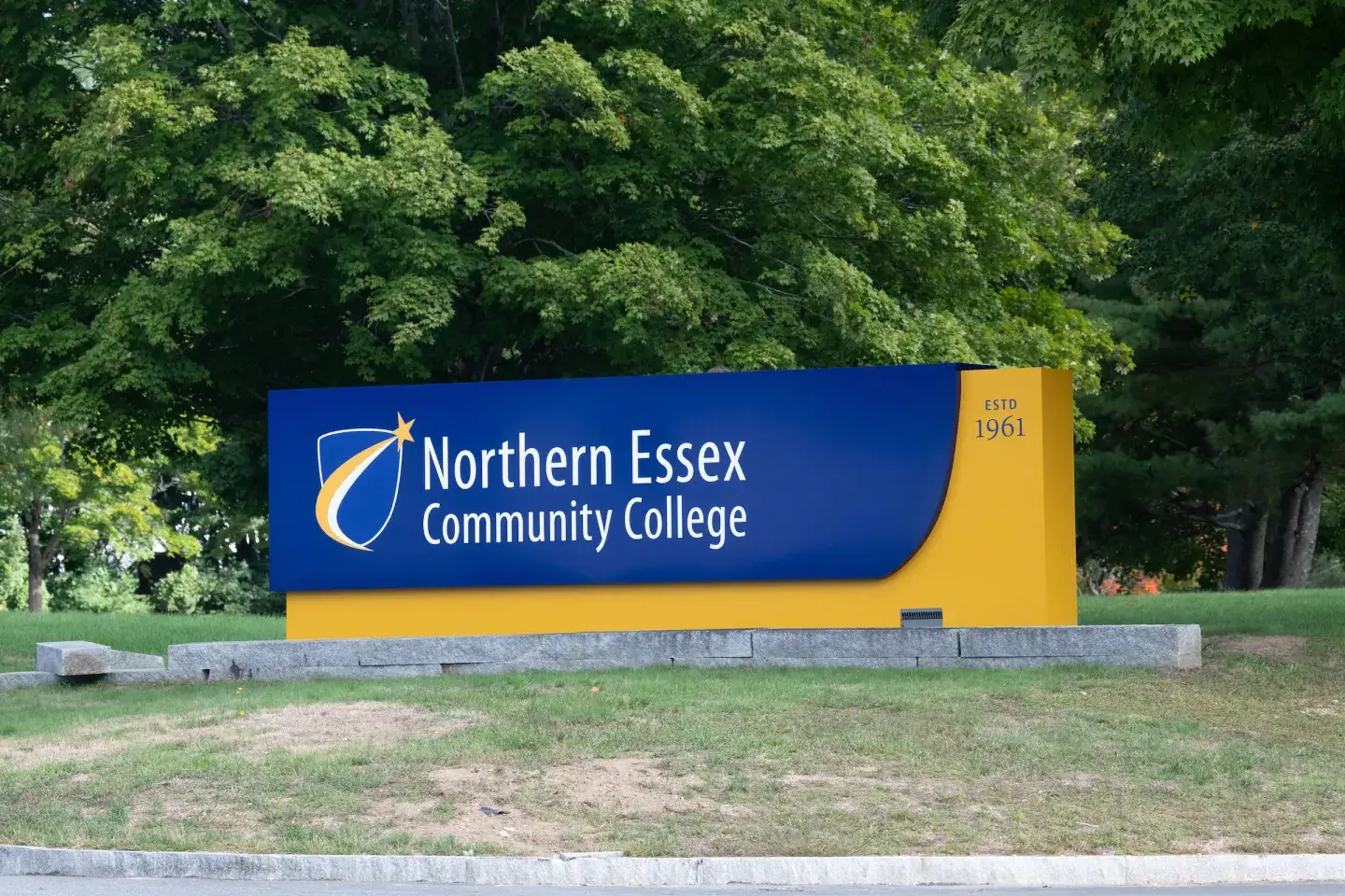 A sign near a wooded area for the Northern Essex Community College