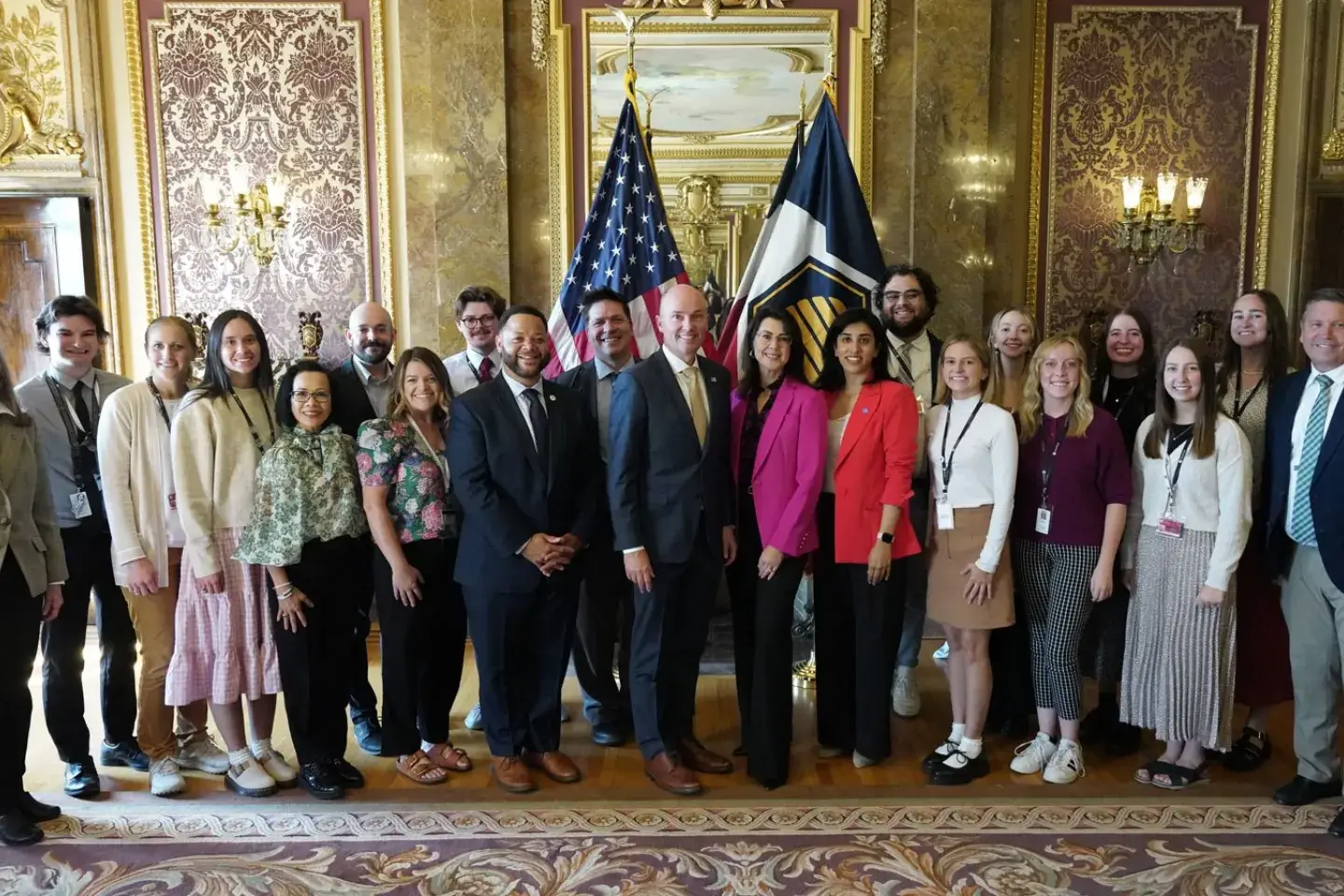 A photo of a large group of people standing in a government building