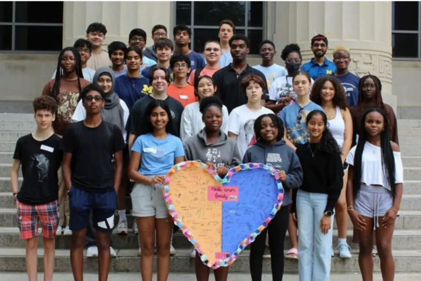 A large group of students holding a large homemade paper heart