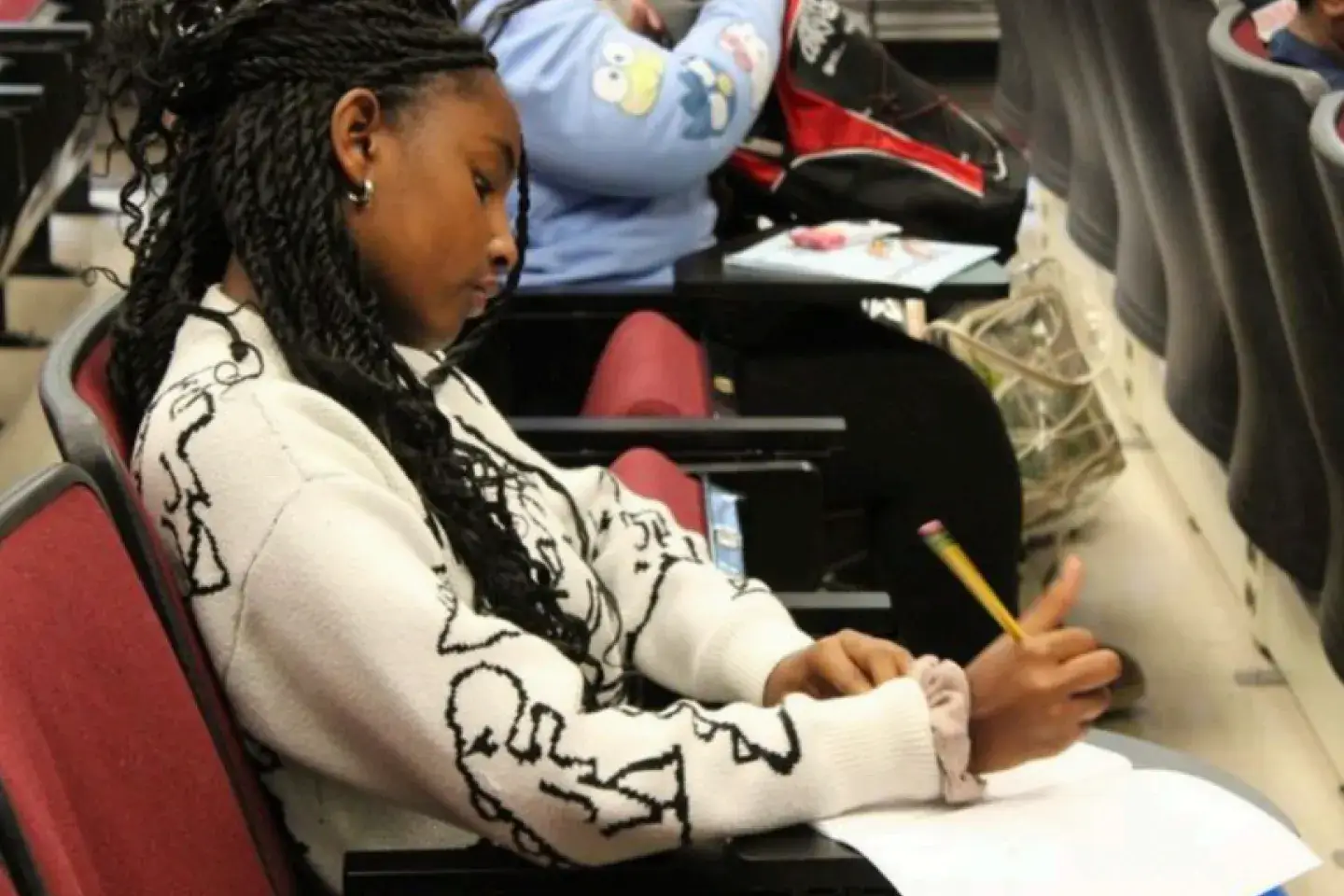 A young female student writing in a notebook in an auditorium