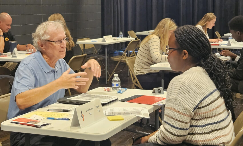 A young student sitting at a table with an older man discussing career opportunities