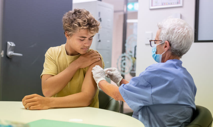 Teenage boy getting vaccination injection in upper arm