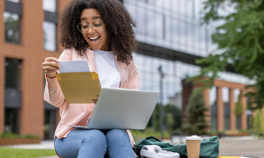 Excited student receiving letter of approval while studying on campus