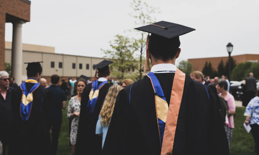A man in a graduation cap and gown walks away from the camera
