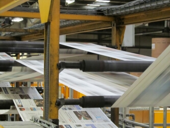Newspaper being printed on large industrial printing press