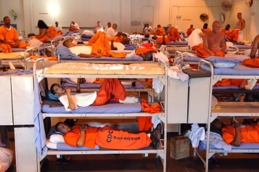 Prisoners sleeping in triple bunk beds stuffed into large room