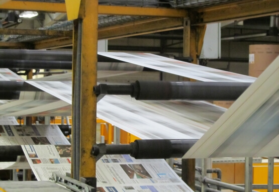 Newspaper being printed on large industrial printing press