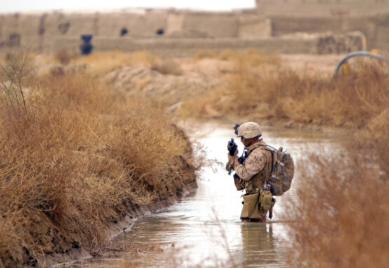 American soldier crosses stream in Afghanistan in 2011